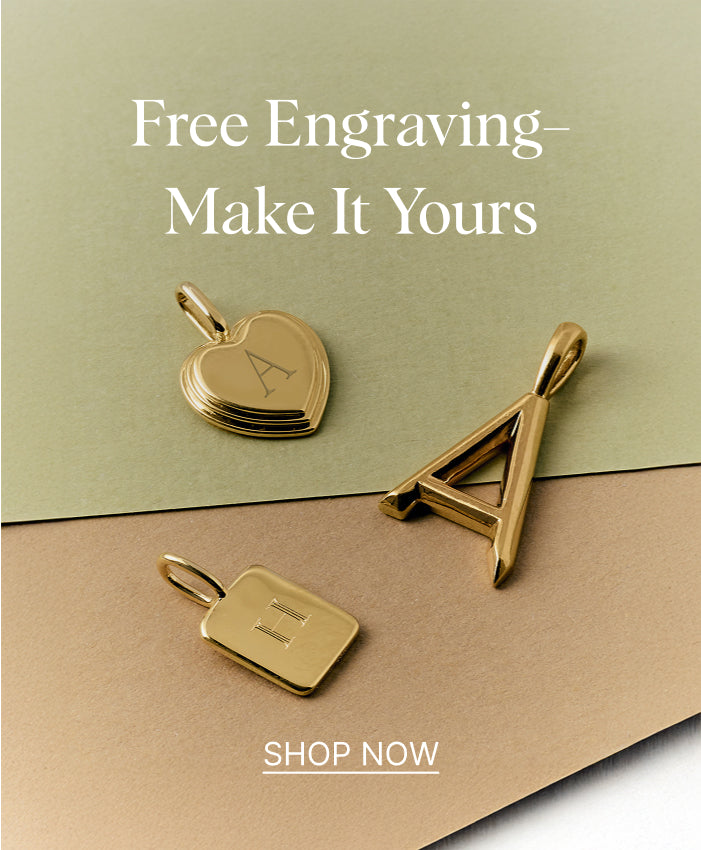 Three solid 14ct gold personalized pendants including a heart, a large letter A, and a square with the letter E displayed on layered green and brown paper with text about free engraving and customization.