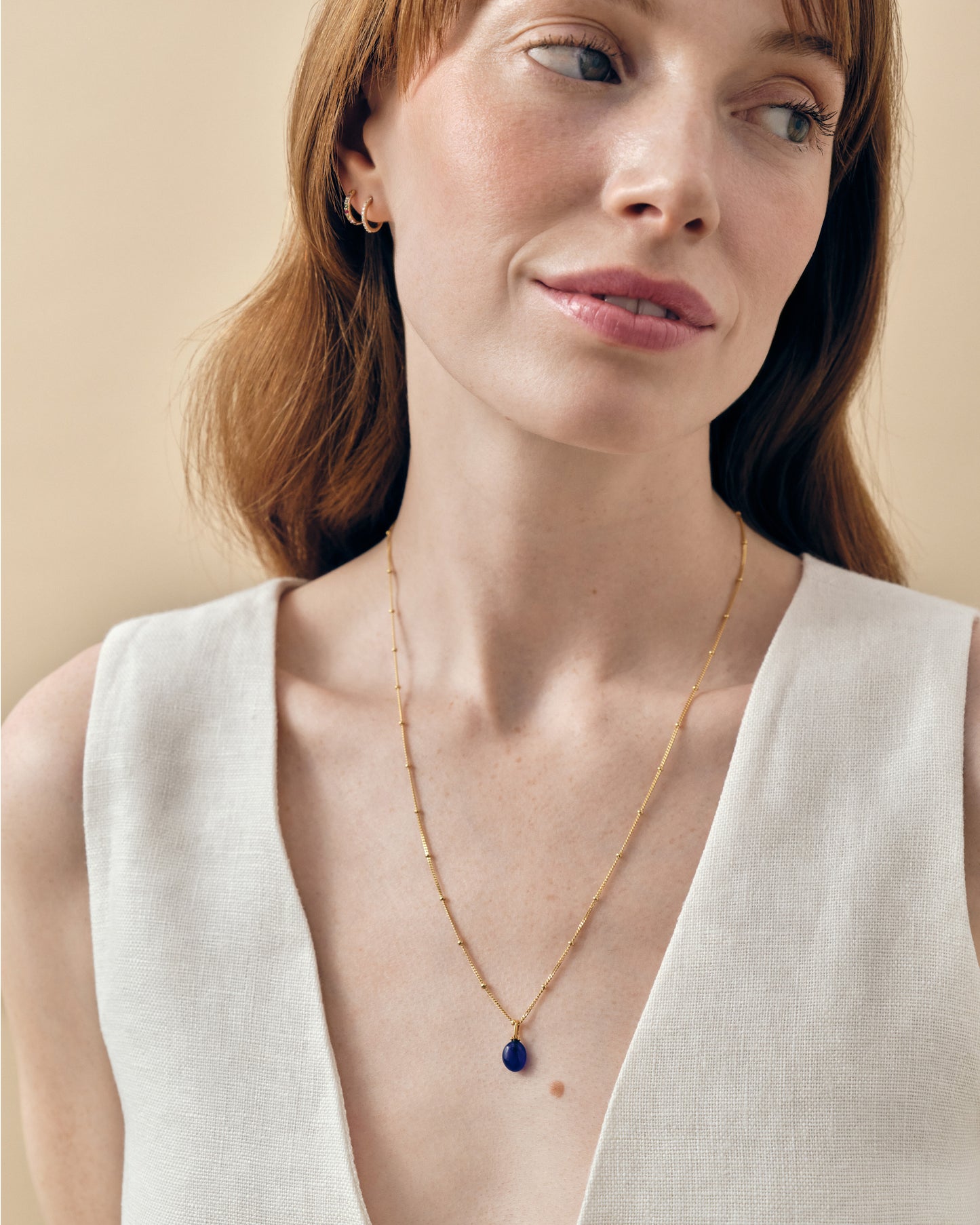 Woman wearing the Coastal Blue Quartz Necklace featuring a gold-plated delicate chain with a deep blue quartz pendant, showcasing considered jewellery made from recycled metals.