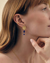 Woman wearing Coastal Blue Quartz Statement Earrings featuring gold-plated stud design with deep blue quartz drops, paired with a delicate gold ear cuff, showcasing sustainable fine jewellery.