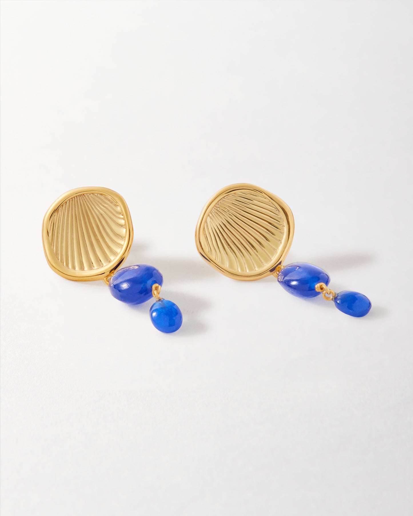 Coastal Blue Quartz Statement Earrings featuring gold-plated stud design with textured shell-like detail and vibrant blue quartz drops, crafted from recycled metals with considered jewellery values.