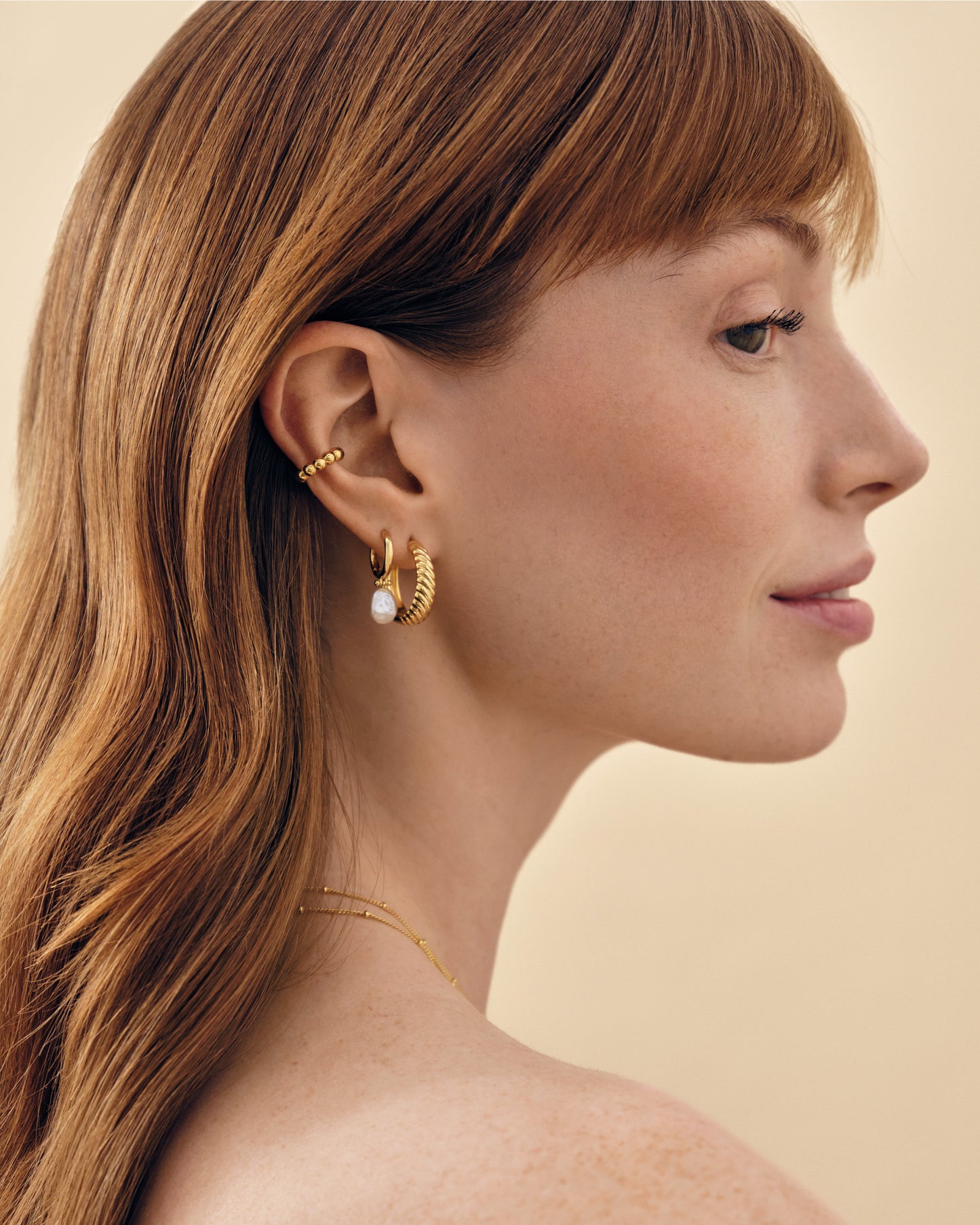 Close-up profile of a woman wearing Coastal Pearl Earrings, featuring stud design in gold-plated sterling silver with a delicate pearl, embodying considered jewellery crafted from recycled metals and ethical sourcing.