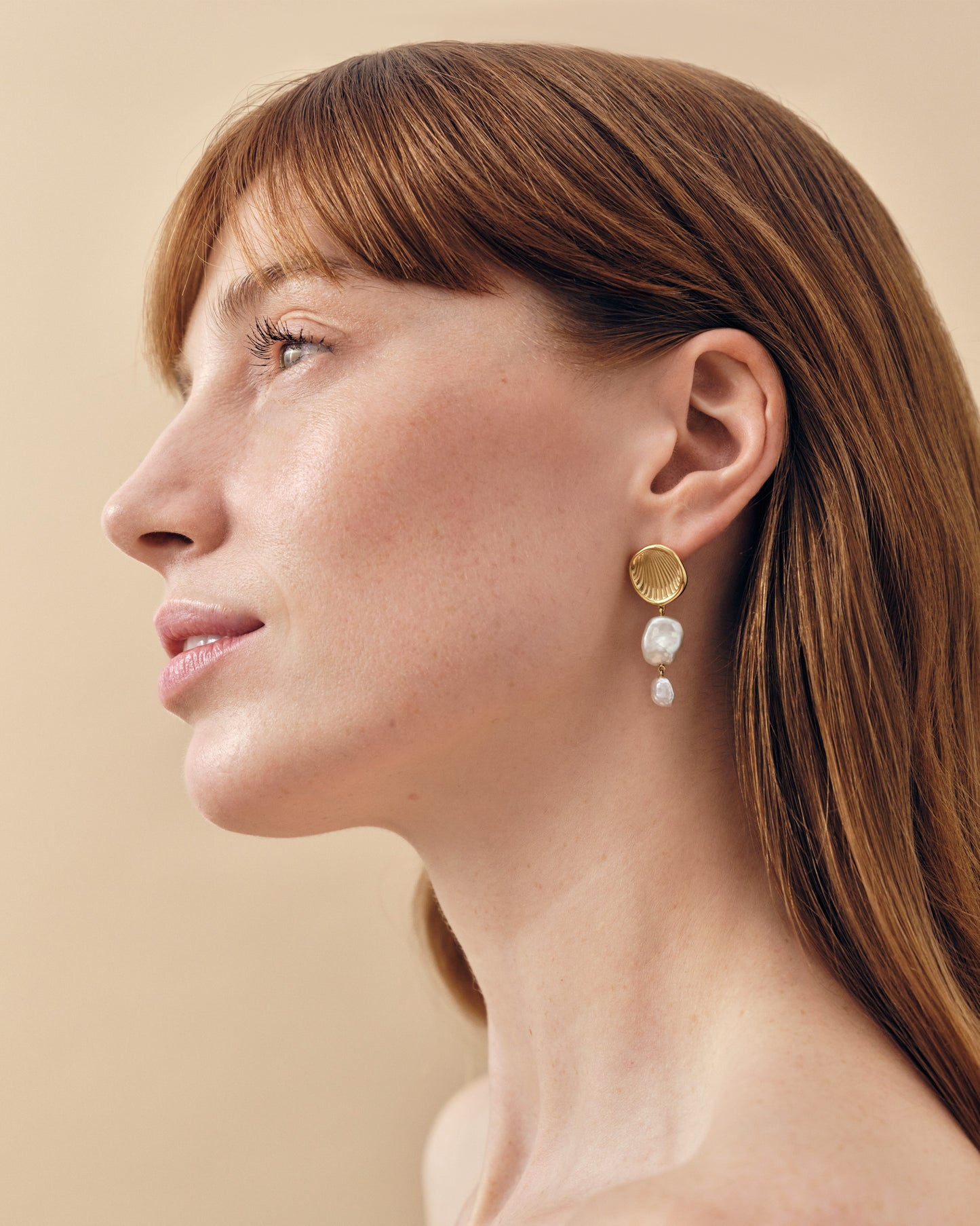 Close-up profile of a woman wearing Coastal Pearl Statement Earrings featuring gold-plated stud design with two delicate sterling silver pearls, showcasing considered jewellery crafted from recycled metals and ethically sourced materials.