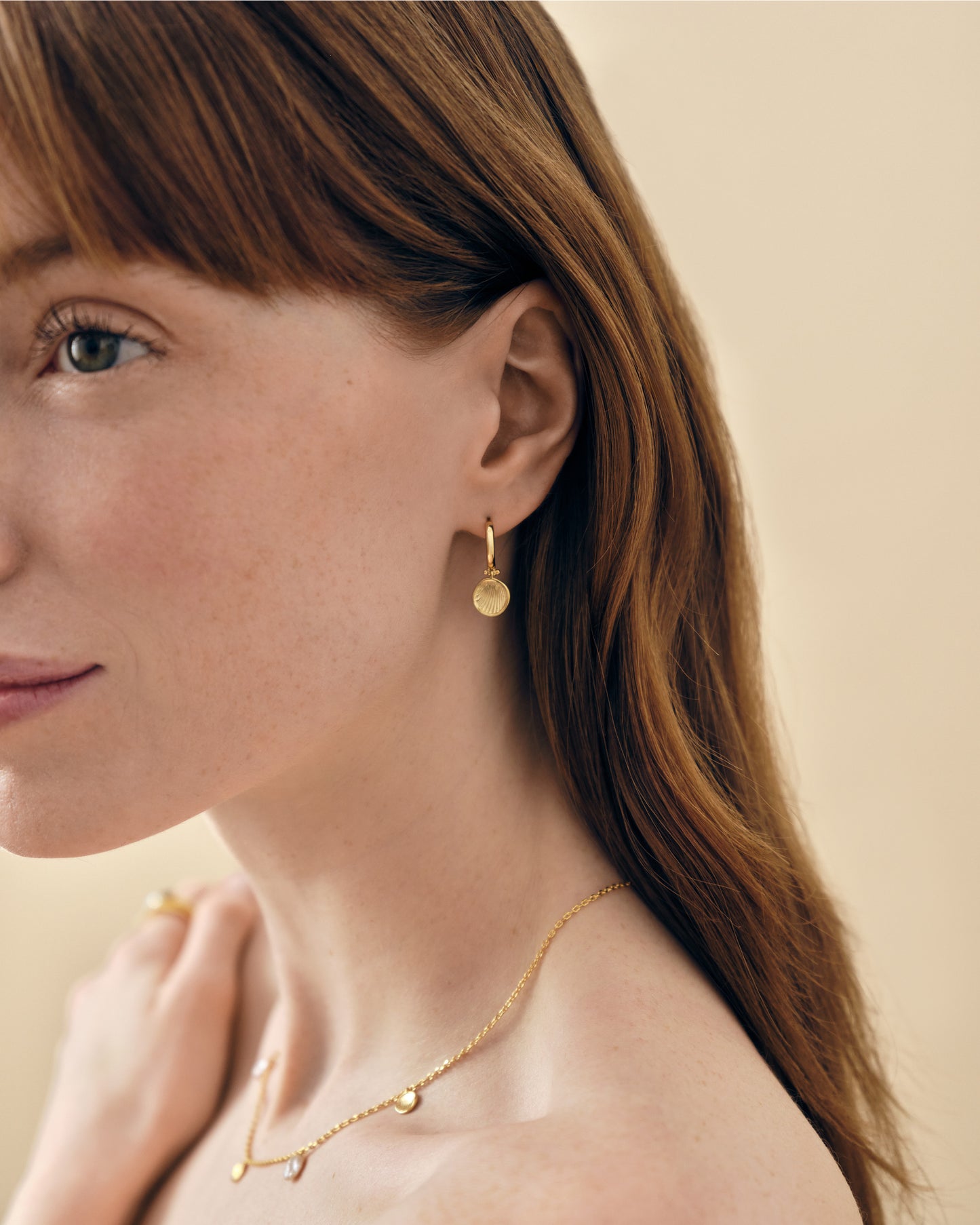 Woman wearing Coastal Shell Earrings gold-plated stud earrings with a matching delicate gold necklace, showcasing sustainable fine jewellery made from recycled metals.
