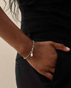 Deco White Topaz Globe Bracelet - Silver worn on wrist with hand in pocket, showcasing sterling silver gemstone chain design for everyday fine jewellery crafted from recycled metals.