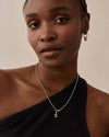 A close-up of a woman wearing the Deco Black Spinel Globe Necklace - Silver made from sterling silver with a delicate pendant and chain, showcasing elegant sustainable fine jewellery designed for everyday luxury.