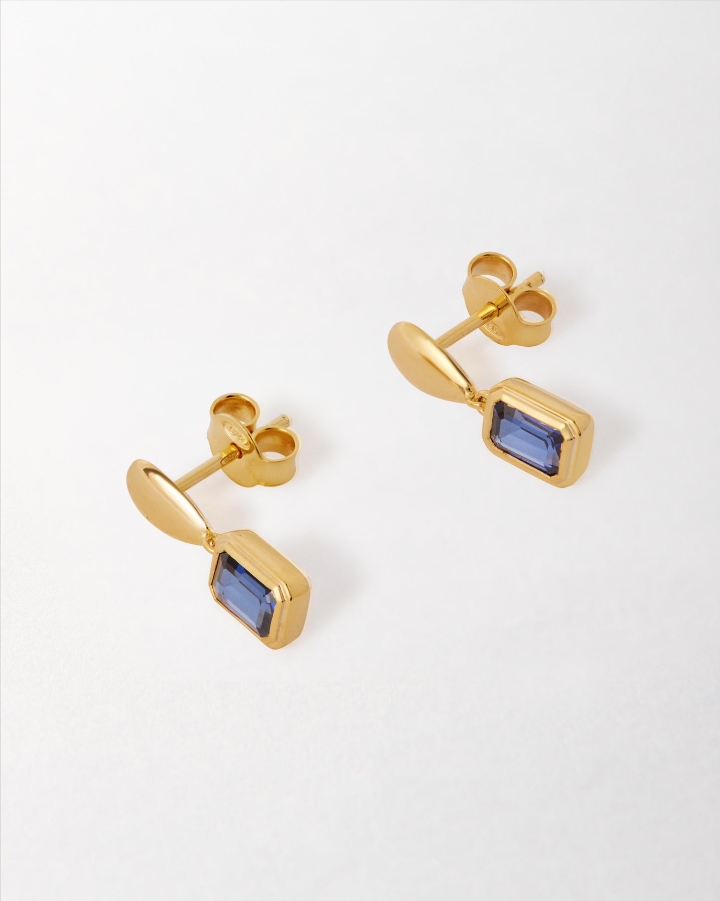 Pebble Blue Sapphire September Birthstone Drop Earrings in gold-plated sterling silver with deep blue sapphire stones, crafted from recycled metals and designed as considered jewellery.