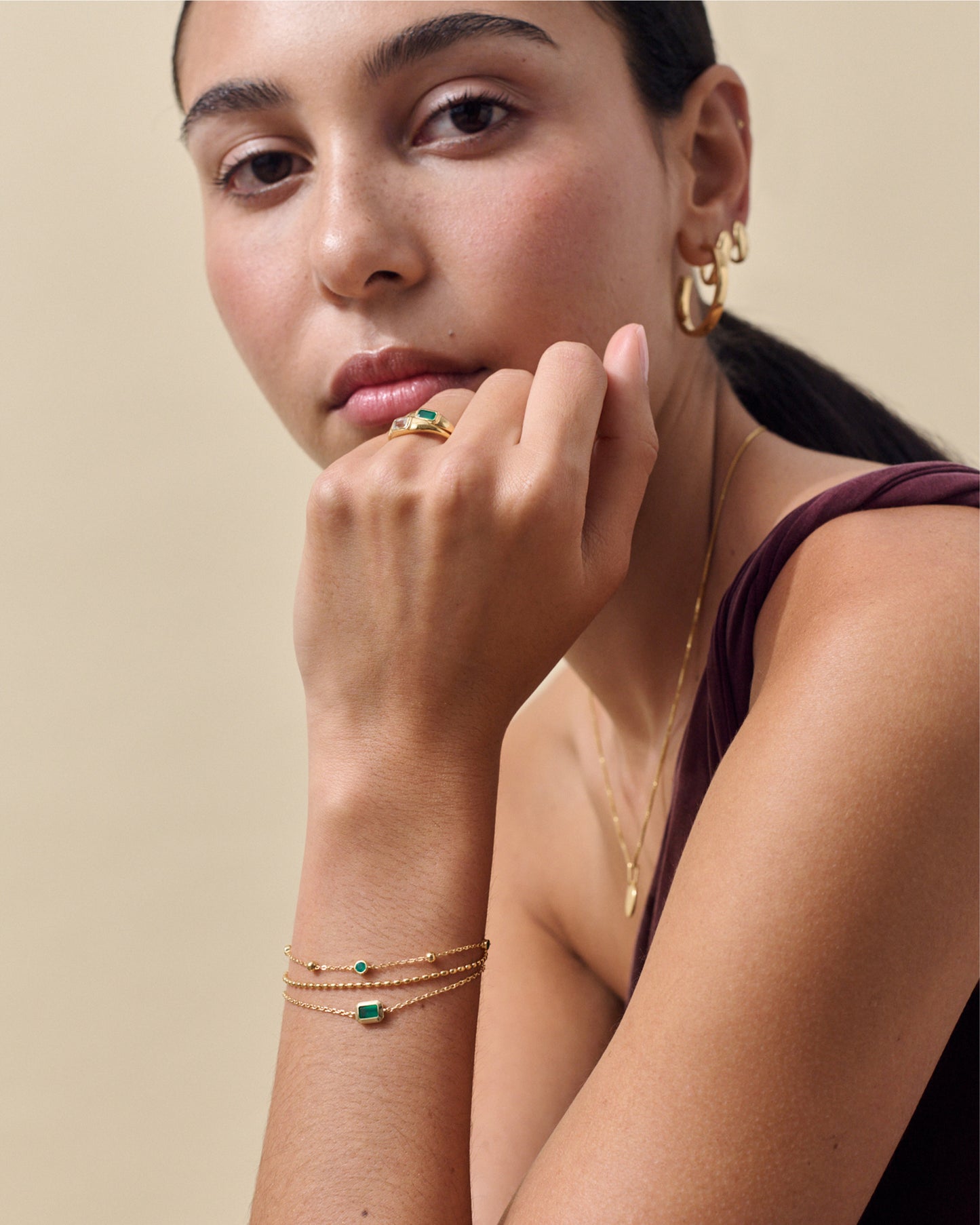 Woman wearing the Pebble Green Onyx Ring made from gold-plated sterling silver, paired with delicate gold bracelets and hoop earrings, showcasing considered jewellery crafted from recycled metals.