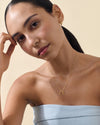 A woman wearing the Double Mini Initial Necklace - Gold featuring delicate gold-plated pendants on a fine chain, embodying considered jewellery made in recycled metals.