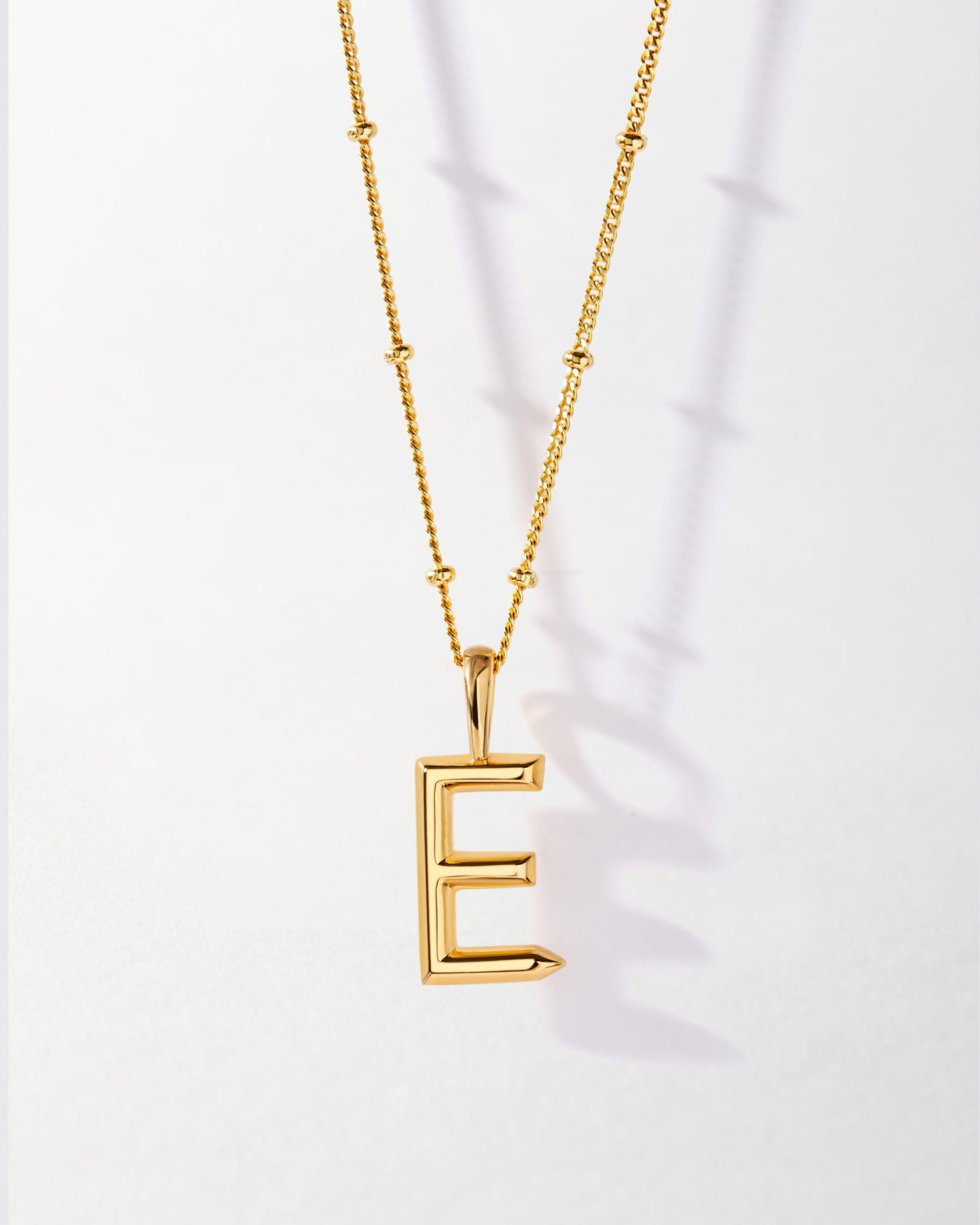 E' Initial Necklace - Gold featuring a gold-plated pendant with letter E on a delicate chain, crafted from recycled metals for considered, sustainable fine jewellery.