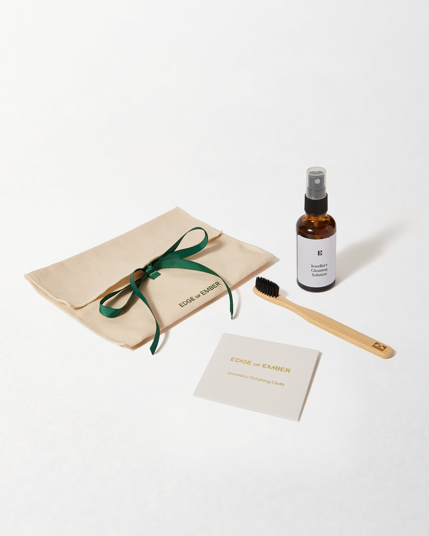Jewellery Care Kit featuring eco-friendly packaging, a bamboo brush, a gentle cleaner in a glass spray bottle, and a care instruction card, reflecting sustainable fine jewellery values.