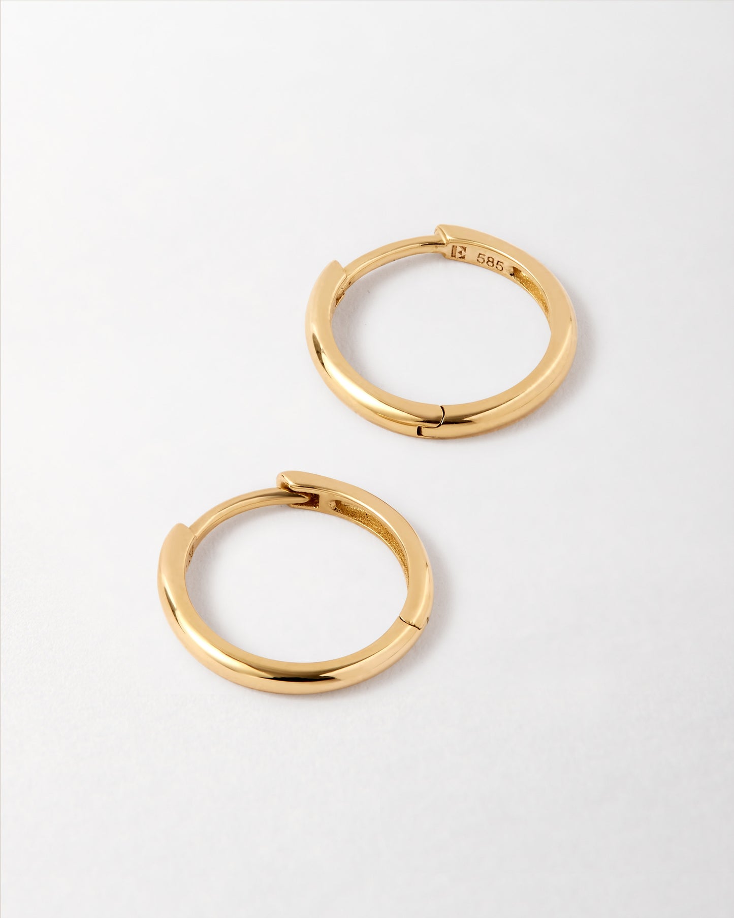 Solid Gold Huggie Hoop Earrings made from recycled 14ct gold, showcasing ethical sourcing and fine craftsmanship with a sleek, timeless design built to last.