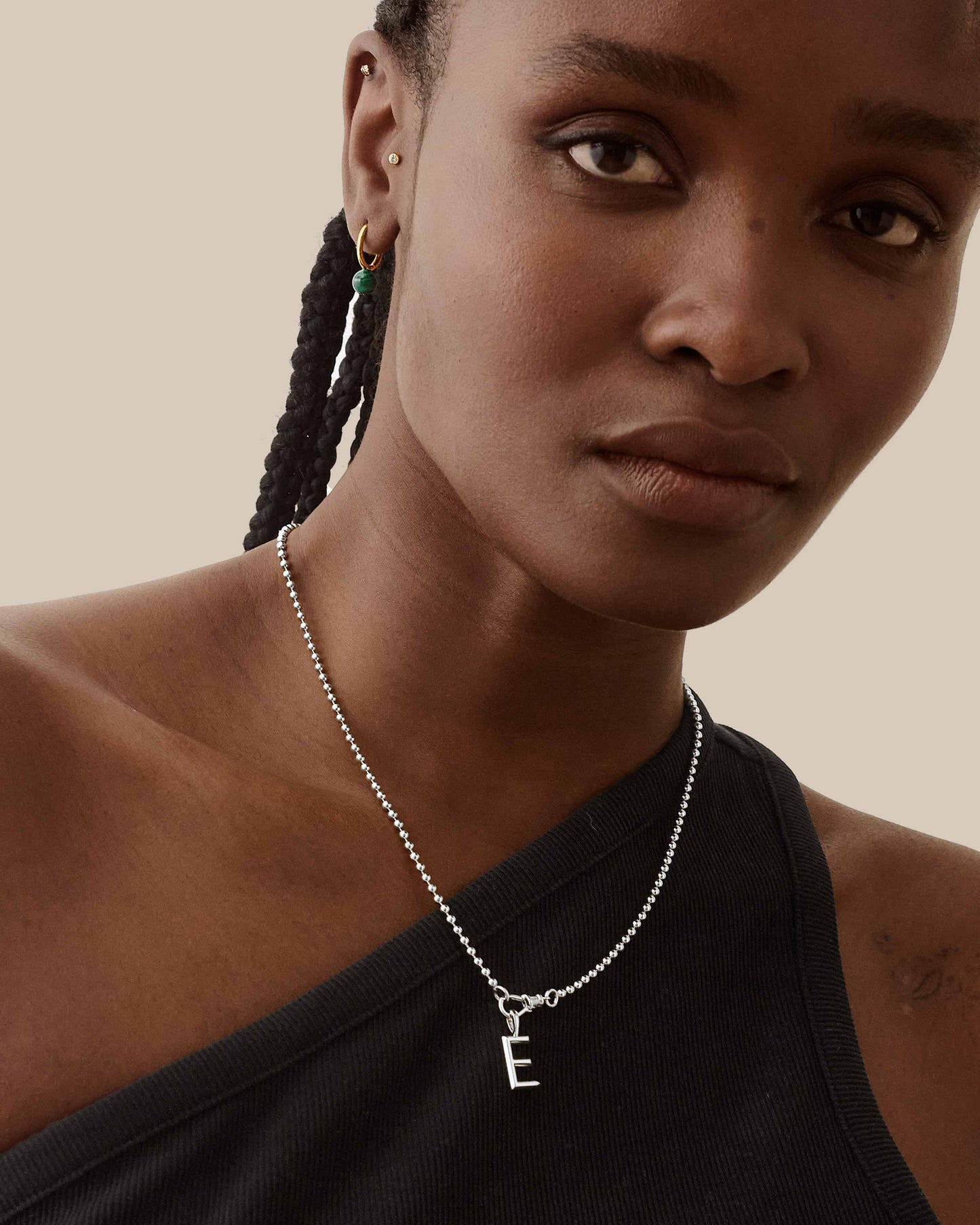 Close-up of a woman wearing the Initial Globe Necklace - Silver, a sterling silver pendant and chain piece made from recycled metals, showcasing considered, fine jewellery designed for everyday wear.