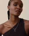 Woman wearing the Initial Globe Necklace - Silver featuring a sterling silver pendant and chain, crafted in recycled metals with ethical sourcing for fine everyday jewellery.