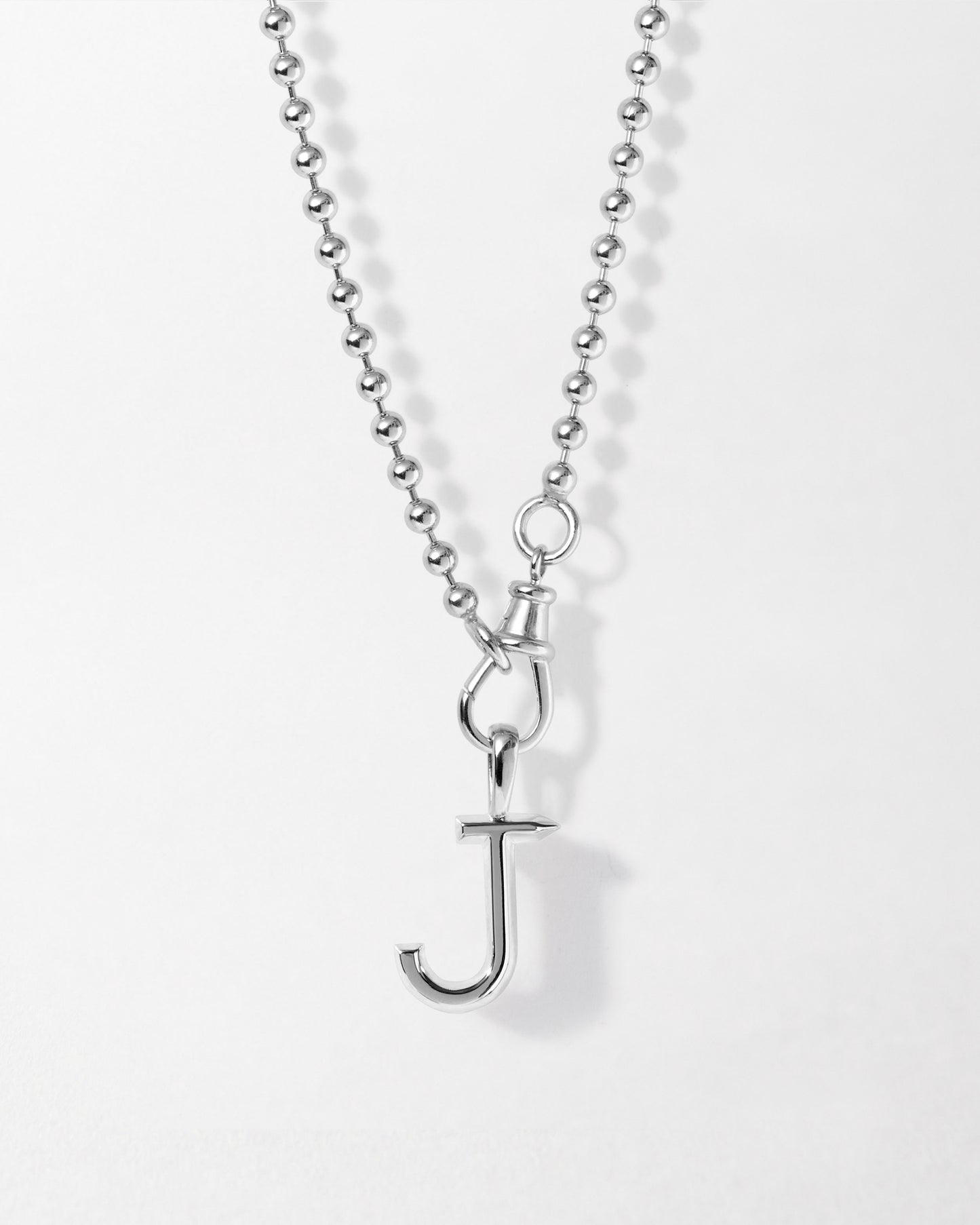 Close-up of the Initial Globe Necklace - Silver featuring a sterling silver chain with a pendant shaped like the letter J, crafted from recycled metals for considered jewellery and everyday fine style.