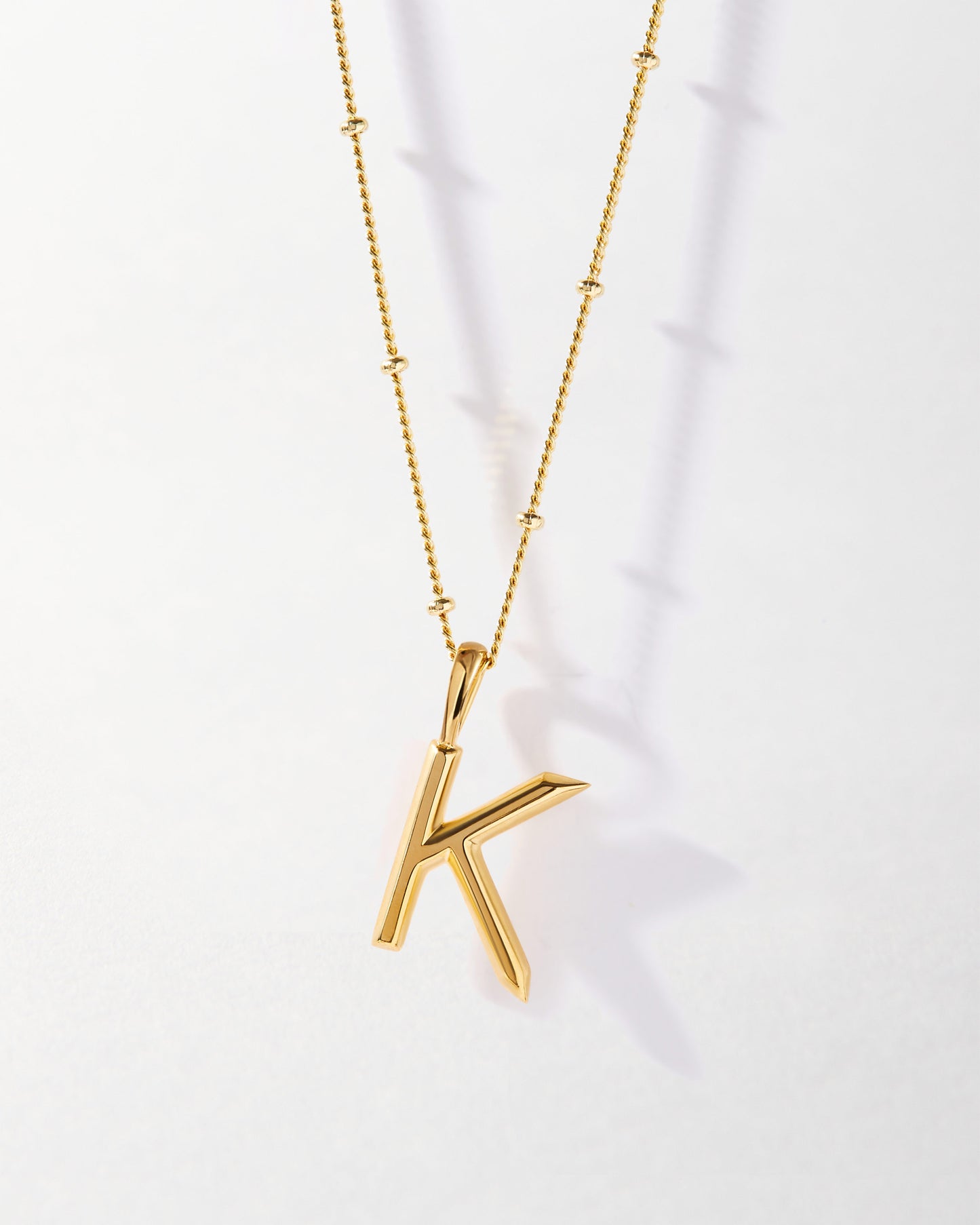 K' Initial Necklace - Gold featuring a gold-plated pendant in the shape of a letter K on a delicate chain, crafted from recycled metals for considered fine jewellery made to last.