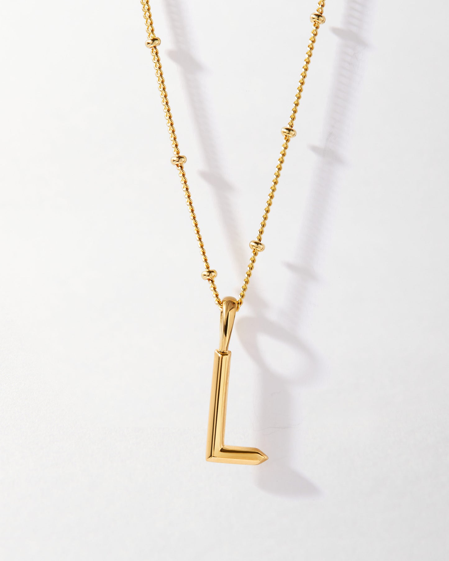 L' Initial Necklace - Gold featuring a gold-plated pendant in the shape of the letter L on a delicate chain, crafted with recycled metals and ethical sourcing.