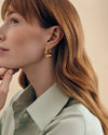 Close-up of a woman wearing Charlotte Collins Large Twist Hoop Earrings in gold-plated sterling silver, showcasing sustainable, fine jewellery made from recycled metals with ethical sourcing.