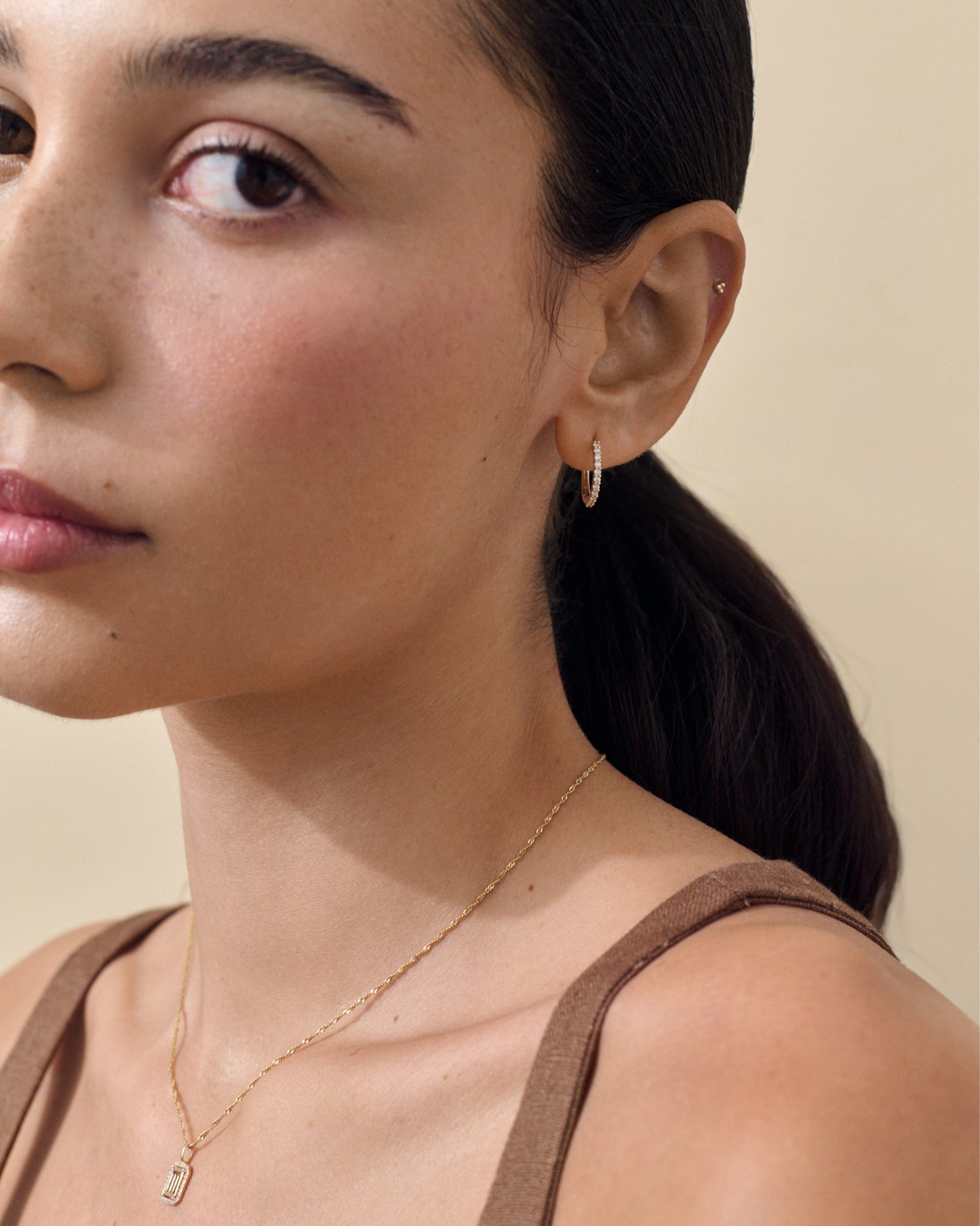 Close-up of a woman wearing Medium Diamond Halo Hoop Earrings made from solid gold with sparkling diamonds, showcasing ethically sourced, recycled metals and fine jewellery craftsmanship.