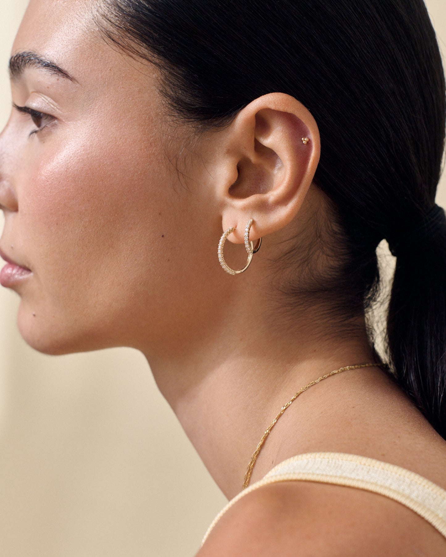 Close-up of a woman wearing Medium Diamond Halo Hoop Earrings crafted in solid gold with lab-grown diamonds, showcasing ethical sourcing and recycled metals for considered jewellery. Solid gold. Fine jewellery for the everyday. Made in recycled metals. Built to last.