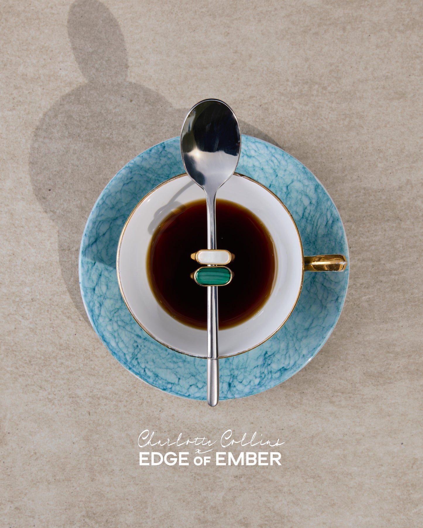 Charlotte Collins Malachite Cocktail Ring featuring a gold-plated and sterling silver design, elegantly displayed on a spoon over a coffee cup with a blue saucer.