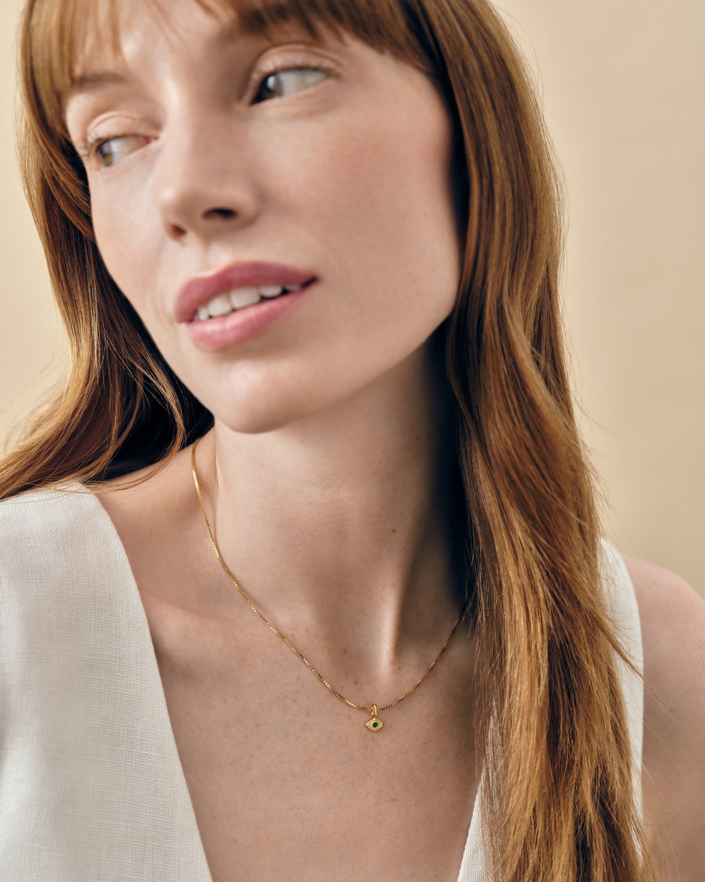 Woman wearing a delicate gold-plated chain with a small Mini Evil Eye Necklace pendant, styled simply against a neutral background.