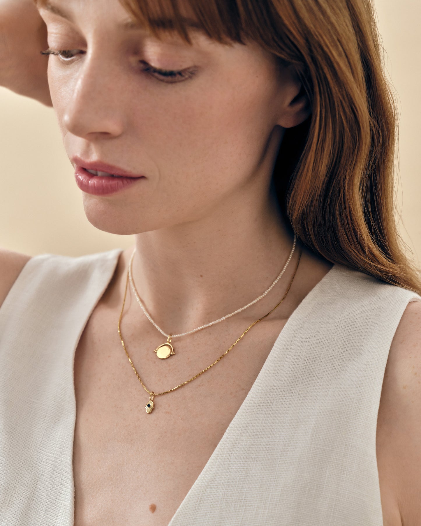 Close-up of a woman wearing the Mini Spinner Pearl Necklace layered with a delicate gold-plated chain, showcasing sustainable, ethically sourced fine jewellery made from recycled metals and sterling silver.