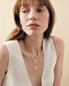 Woman wearing layered gold necklaces featuring a Mini Spinner Pendant made from gold-plated and sterling silver, showcasing considered jewellery built to last with ethical sourcing.