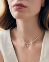 Close-up of a woman wearing a Mini Shell Pearl Necklace featuring a gold-plated shell pendant on a delicate sterling silver chain, crafted with recycled metals for fine everyday jewellery.