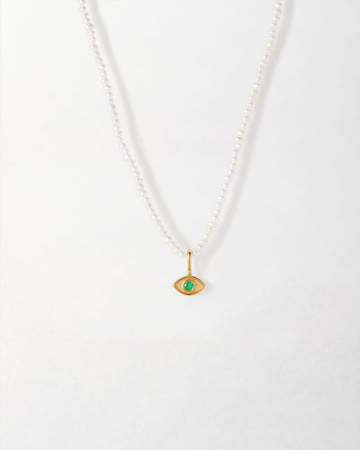 Mini Evil Eye Pearl Necklace featuring a gold-plated pendant with a green stone on a sterling silver pearl chain, crafted from recycled metals and ethically sourced.