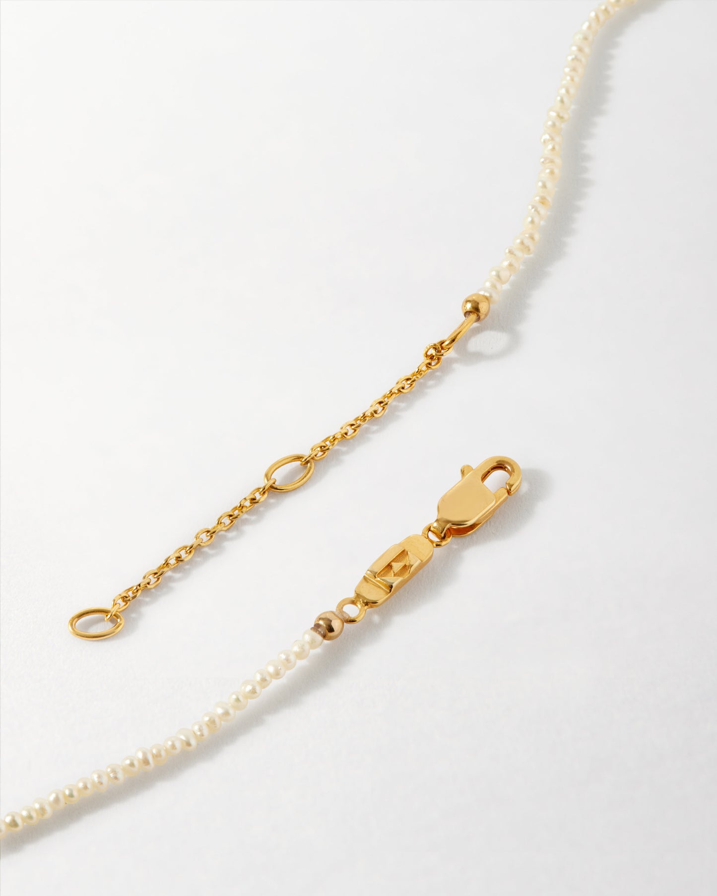 Close-up of the Mini Hamsa Pearl Necklace showing its gold-plated chain and delicate pearl strand, crafted with recycled metals and designed for everyday fine jewellery.