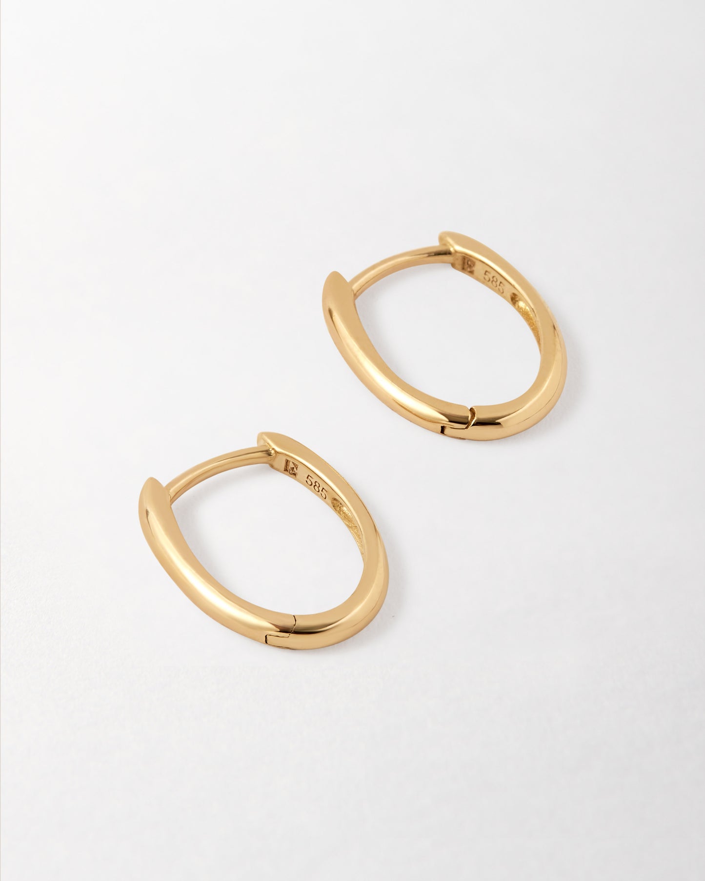Solid Gold Oval Hoop Earrings crafted in recycled 14ct solid gold, featuring a sleek huggie design perfect for everyday fine jewellery with ethical sourcing.