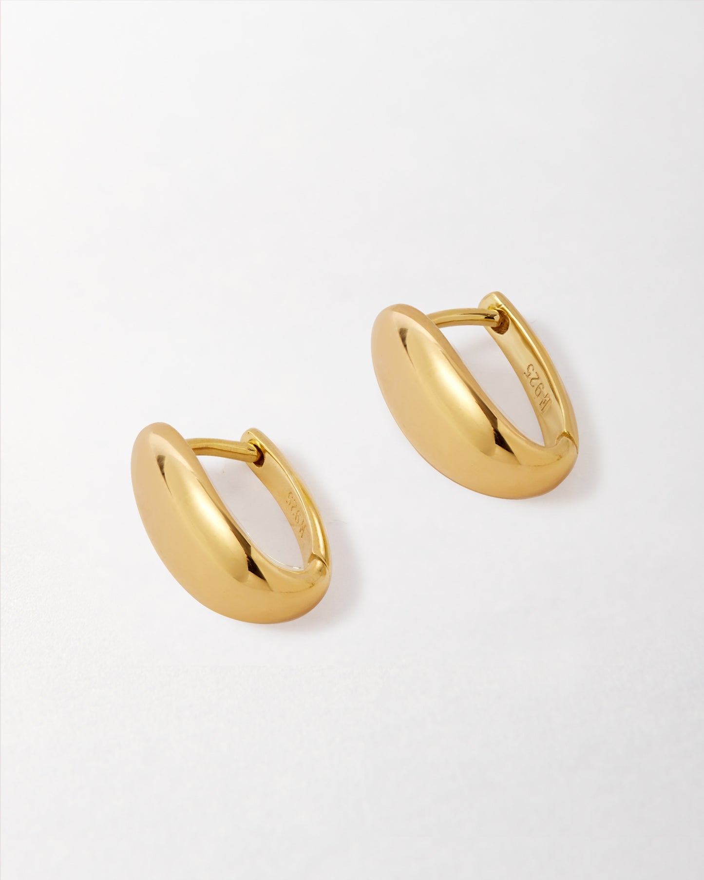 A pair of Pebble Hoop Earring - Gold made from gold-plated sterling silver, showcasing a smooth dangle hoop design crafted with recycled metals for considered everyday fine jewellery.