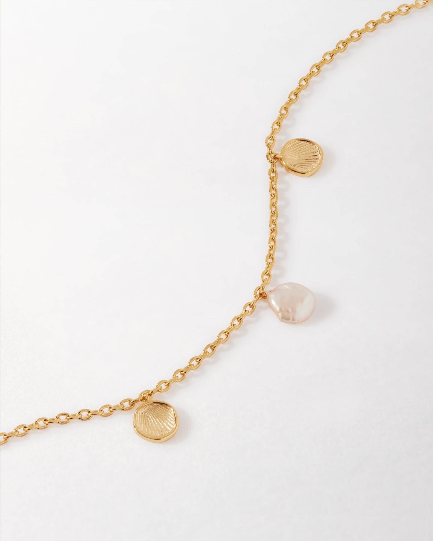 Coastal Shell and Pearl Bracelet featuring a gold-plated chain with delicate shell charms and a natural pearl, crafted from recycled metals for ethical fine jewellery.