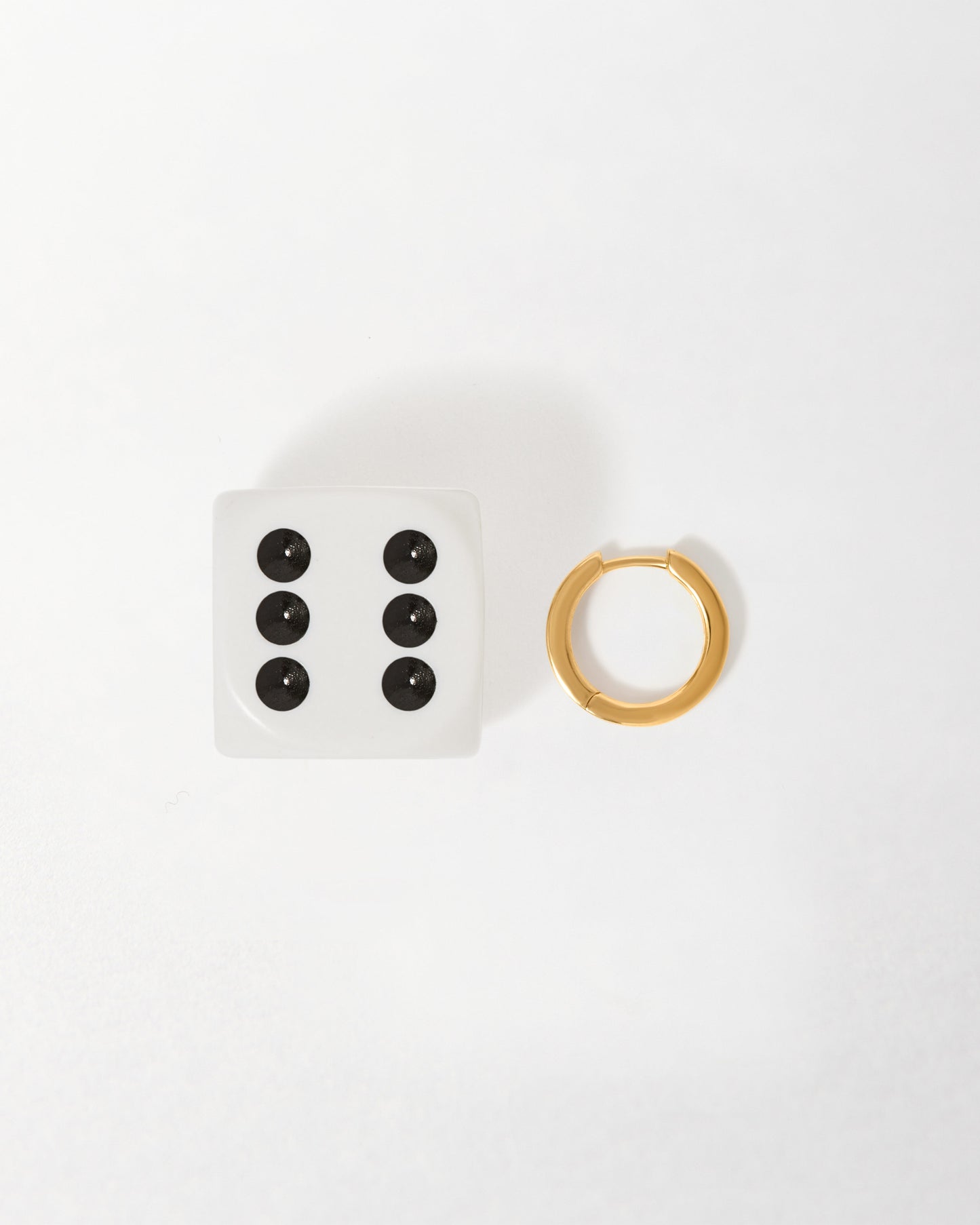 Opal Huggie Earrings in solid gold next to a white dice, showcasing considered jewellery made from recycled metals and designed for everyday fine wear.