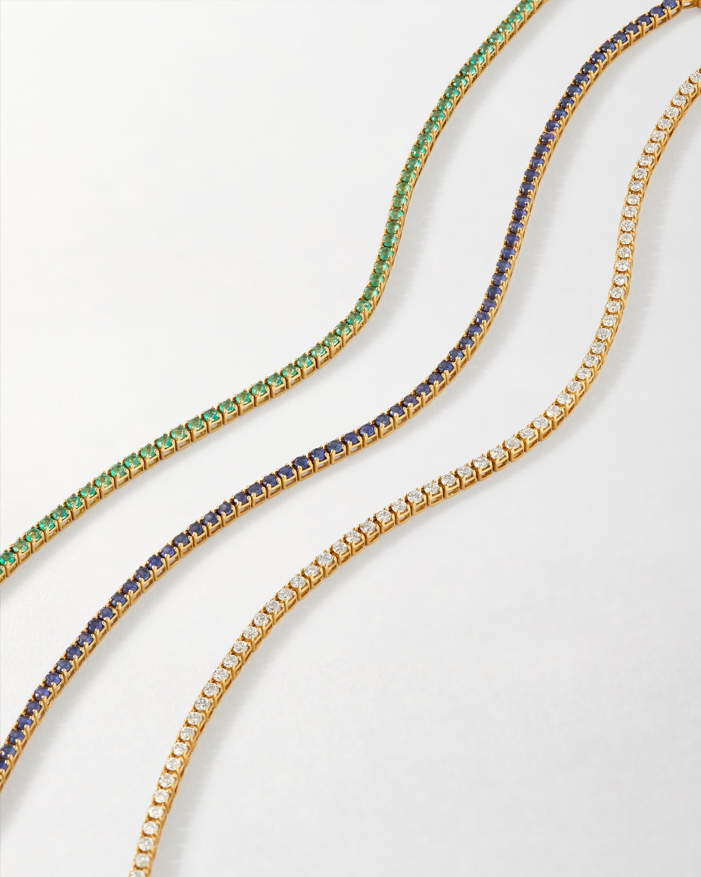 Three elegant tennis bracelets made from solid gold featuring green, blue, and clear lab-grown sapphires and diamonds, showcasing the Solid Gold Lab-Grown Sapphire Tennis Bracelet’s fine craftsmanship and ethical sourcing.