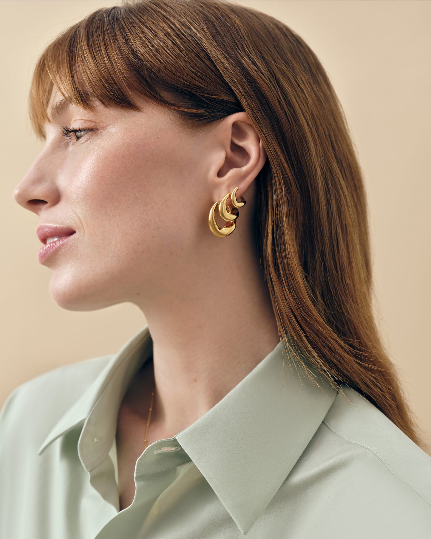 Woman wearing Charlotte Collins Small Twist Hoop Earrings in gold-plated sterling silver, showcasing elegant twist design with sustainable, ethically sourced materials for everyday fine jewellery.