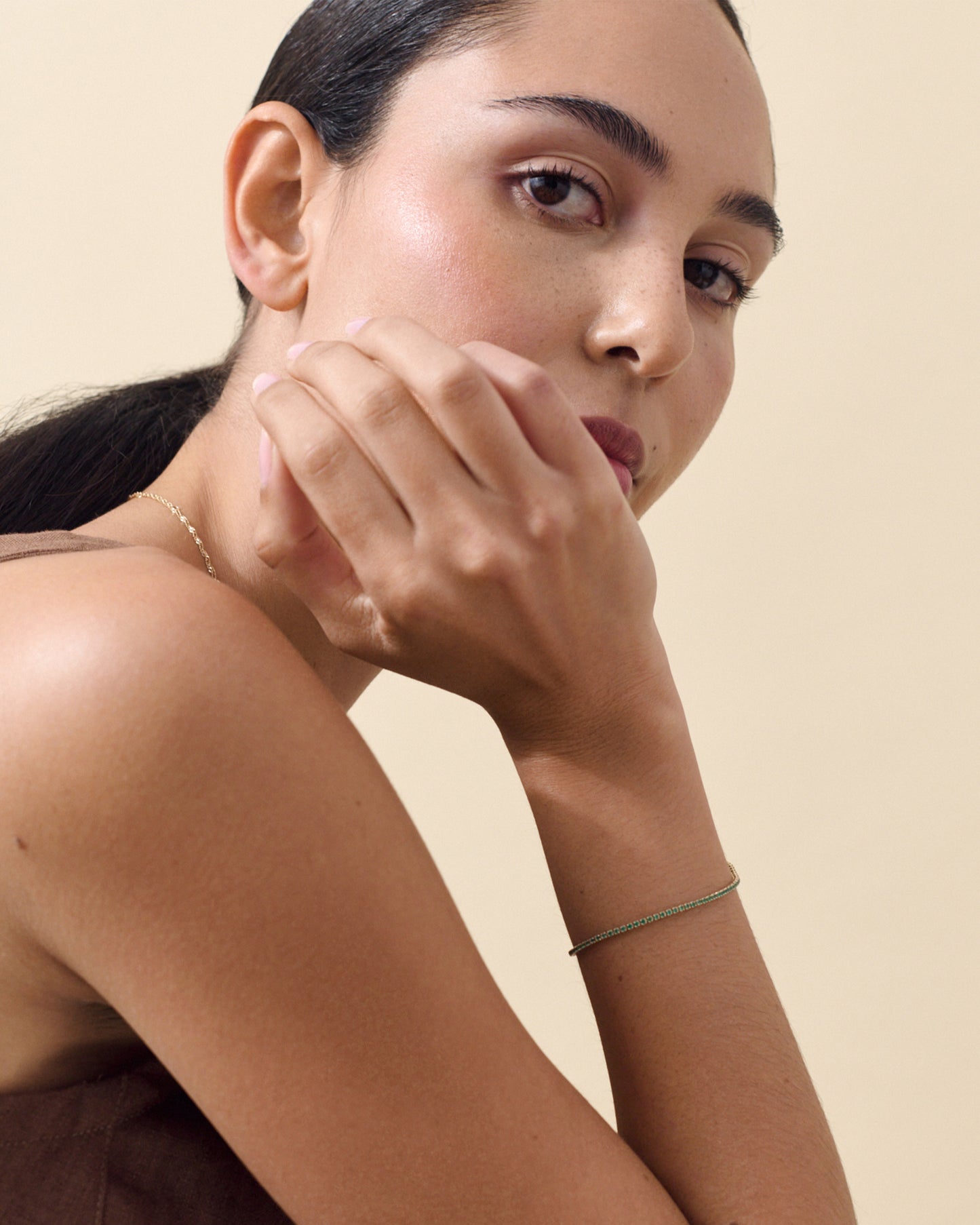 Woman wearing a Solid Gold Lab-Grown Emerald Tennis Bracelet on her wrist, showcasing fine sustainable jewellery crafted with recycled metals and ethical sourcing.