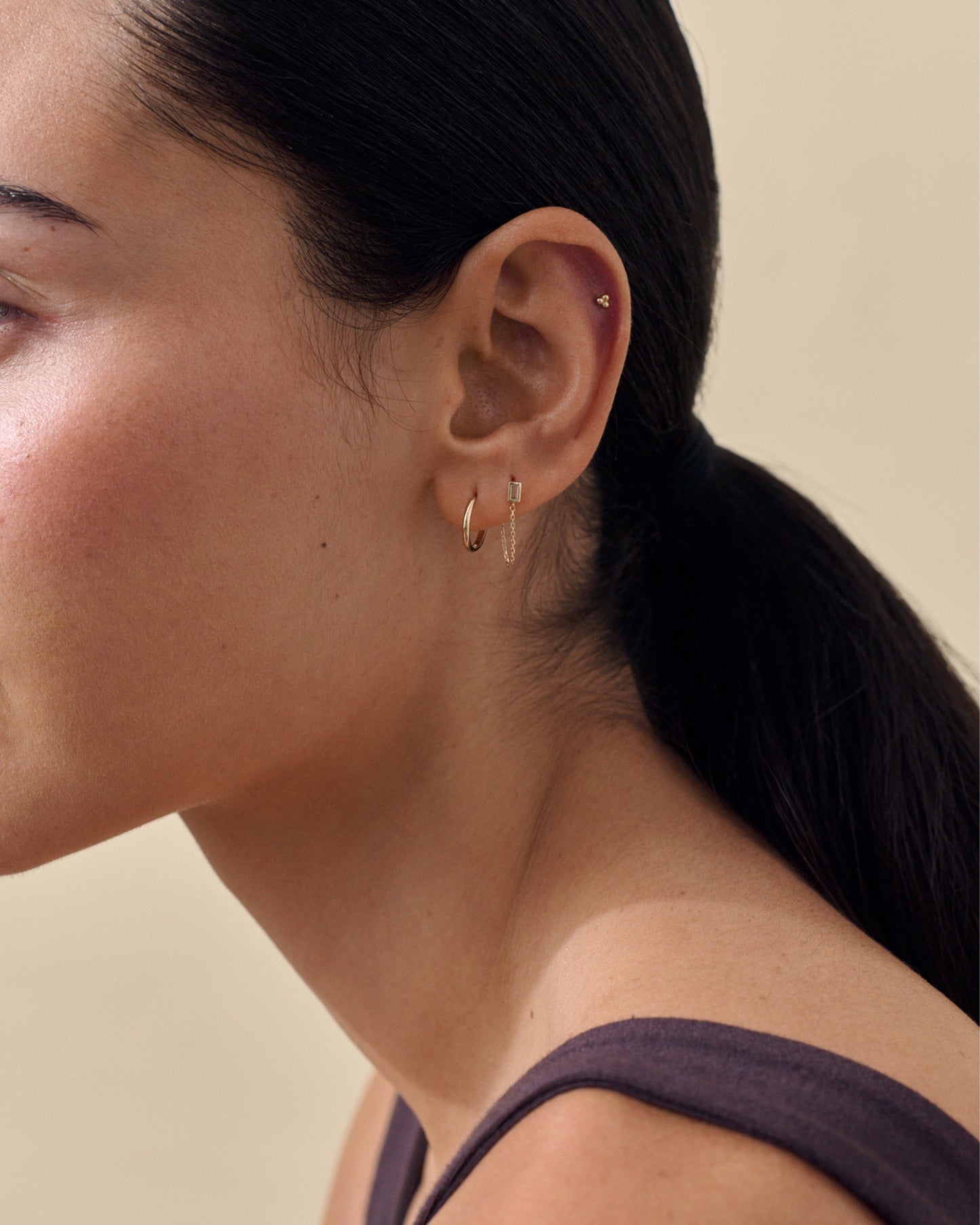 Close-up of a woman wearing Solid Gold Huggie Hoop Earrings, crafted from recycled solid gold, showcasing considered jewellery designed for everyday elegance and ethical style.