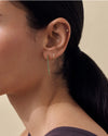 Close-up of a woman wearing Solid Gold Mini Huggie Hoop Earrings, crafted from ethical recycled metals, showcasing fine jewellery designed for everyday luxury and built to last.