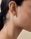 Close-up of a woman's ear wearing Solid Gold Oval Hoop Earrings made from recycled metals, showcasing considered jewellery crafted in solid gold, perfect for everyday fine style.