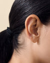 Close-up of a person’s ear wearing a Solid Gold Star Piercing Earring, a delicate gold stud crafted from recycled metals, showcasing considered jewellery for the everyday.