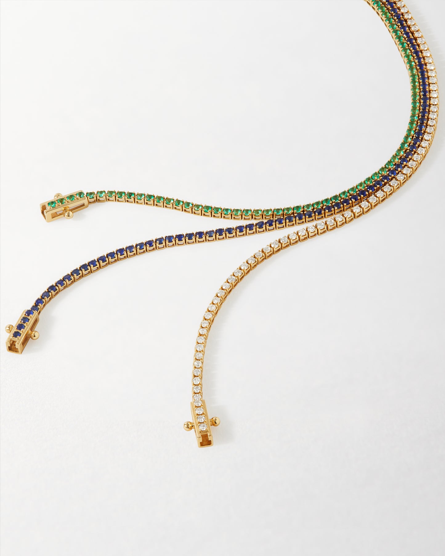 Three elegant tennis bracelets in solid gold featuring lab-grown sapphires, diamonds, and green gemstones, showcasing eco-friendly, ethically sourced fine jewellery like the Solid Gold Lab-Grown Sapphire Tennis Bracelet.