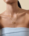 Woman wearing a delicate Triple Mini Initial Necklace - Gold with three gold-plated pendants on a fine chain, showcasing considered jewellery made in recycled metals and built to last.