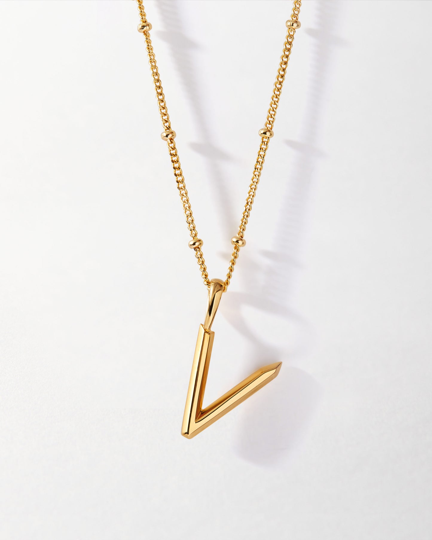 V' Initial Necklace - Gold featuring a sleek gold-plated pendant on a delicate chain, crafted with recycled metals and designed as fine jewellery for everyday wear.