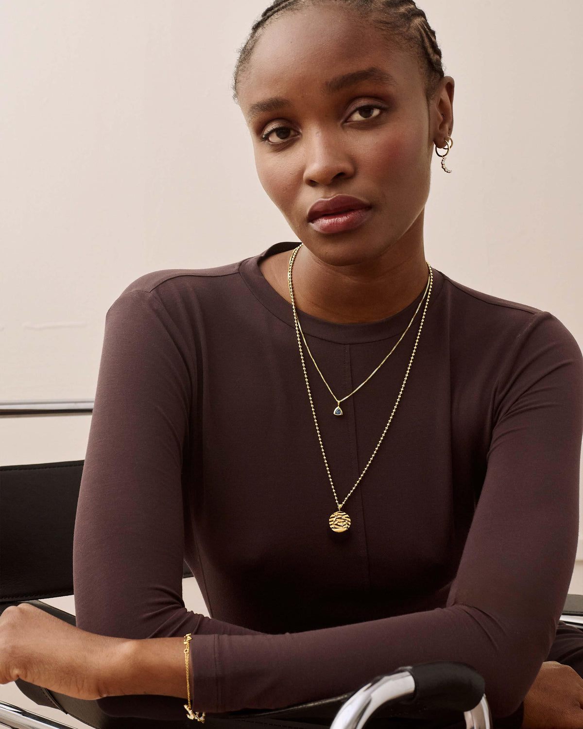 Model wearing the Zodiac Globe Necklace with a delicate gold chain and globe pendant layered over a fine jewellery necklace