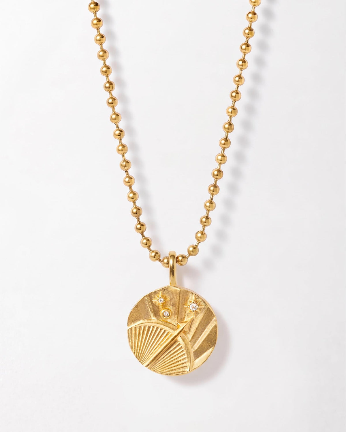 Zodiac Globe Necklace in gold with a round textured pendant and beaded chain on a white background