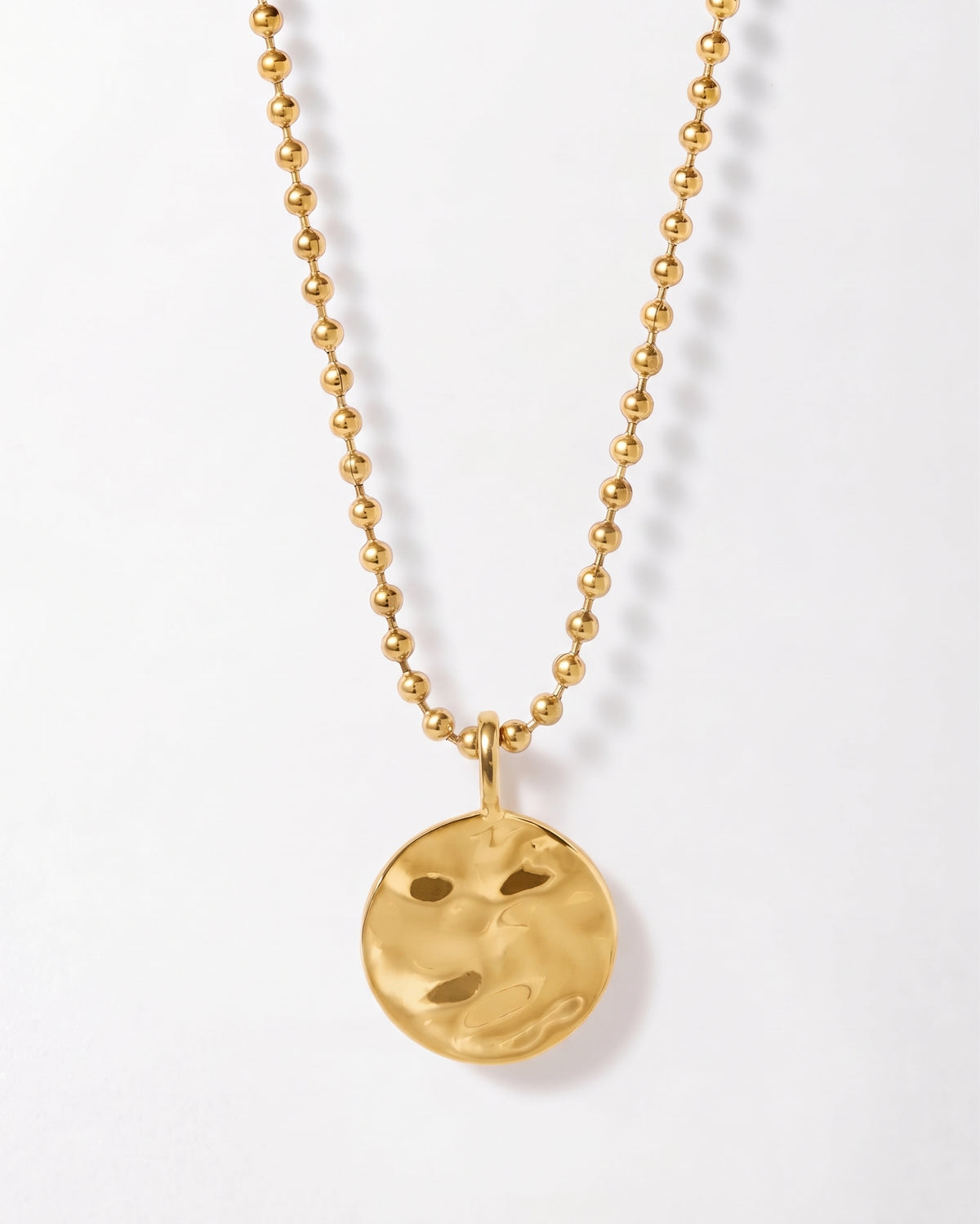 Coin Globe Necklace with a gold plated round pendant and beaded chain on a white background