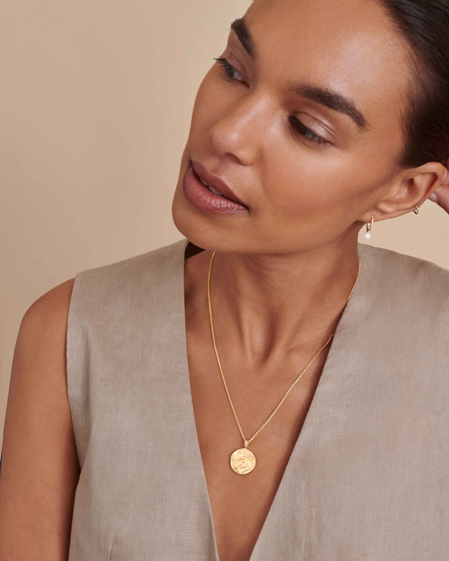 Woman wearing a Zodiac Horoscope Pendant necklace crafted from solid 14ct gold with lab-grown diamond accents, made from recycled metals for ethical fine jewellery.