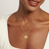 Close-up of a smiling woman wearing a Cancer Zodiac Necklace crafted in solid 14ct gold with a textured pendant on a delicate gold chain, made from recycled metals and ethically sourced.